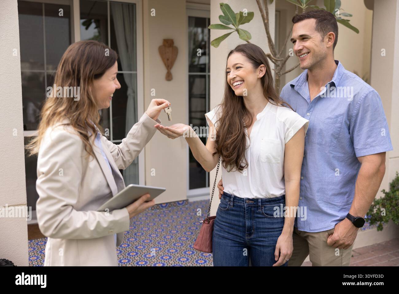 Agente immobiliare che dà le chiavi della casa a una coppia felice Foto Stock