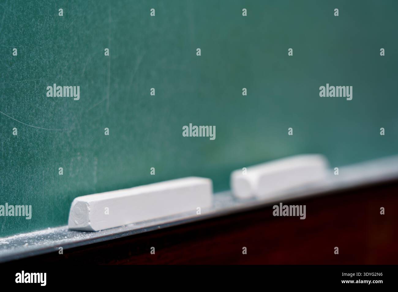 Il gesso poggia sulla sporgenza di una lavagna in classe durante una sessione scolastica Foto Stock
