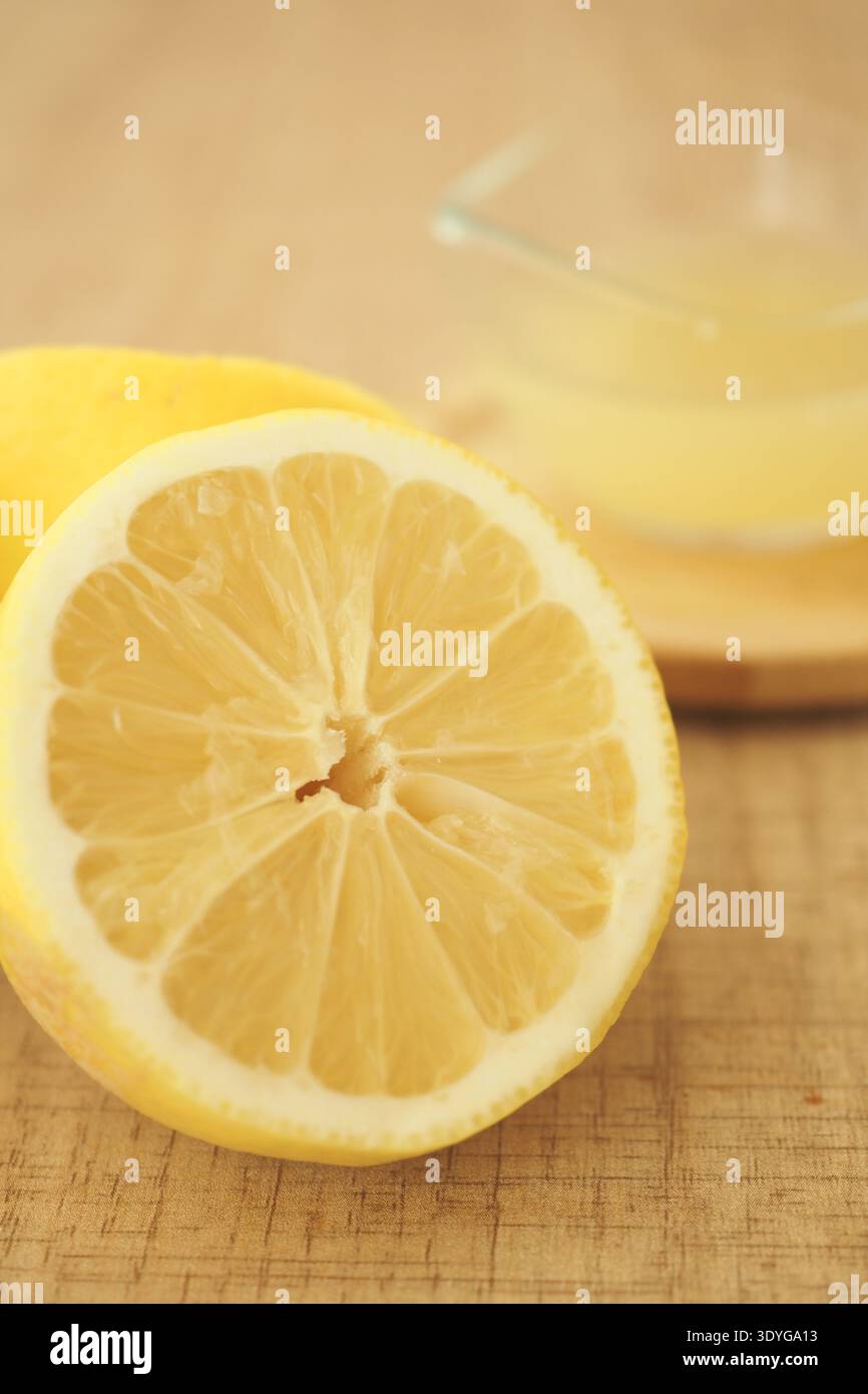 Limone tagliato a metà su un tavolo di legno con succo di limone nelle vicinanze Foto Stock