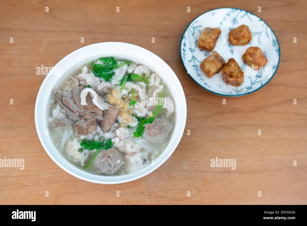 Zuppa di maiale in stile cantonese con gnocchi e tofu fritto servita su un tavolo di legno a Hong Kong Foto Stock