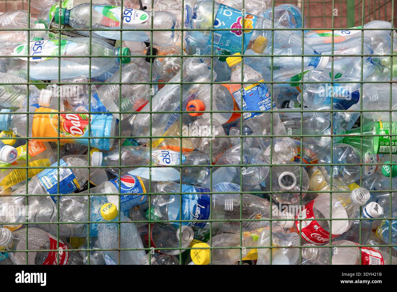 Bishkek , Kirghizistan - 27 agosto 2021 : bottiglie di plastica di varie marche raccolte per il riciclaggio in un contenitore di filo metallico. Bevanda di plastica usata Foto Stock