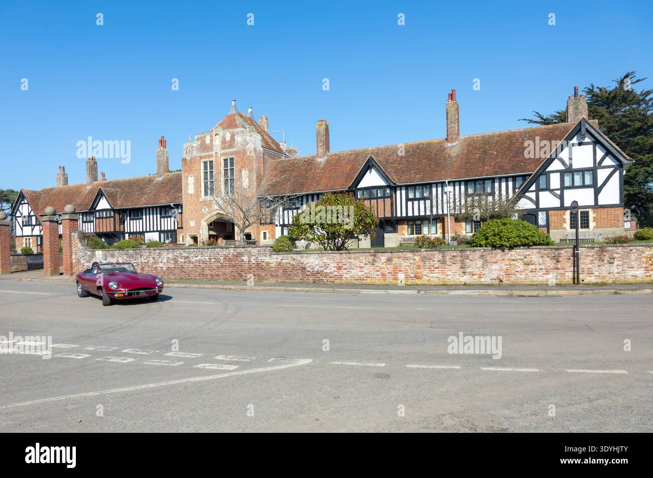 Margaret Ogilvie Almshouses costruita nel 1926, Thorpeness, Suffolk, Inghilterra, Regno Unito con Jaguar e-Type roadster open top car Foto Stock