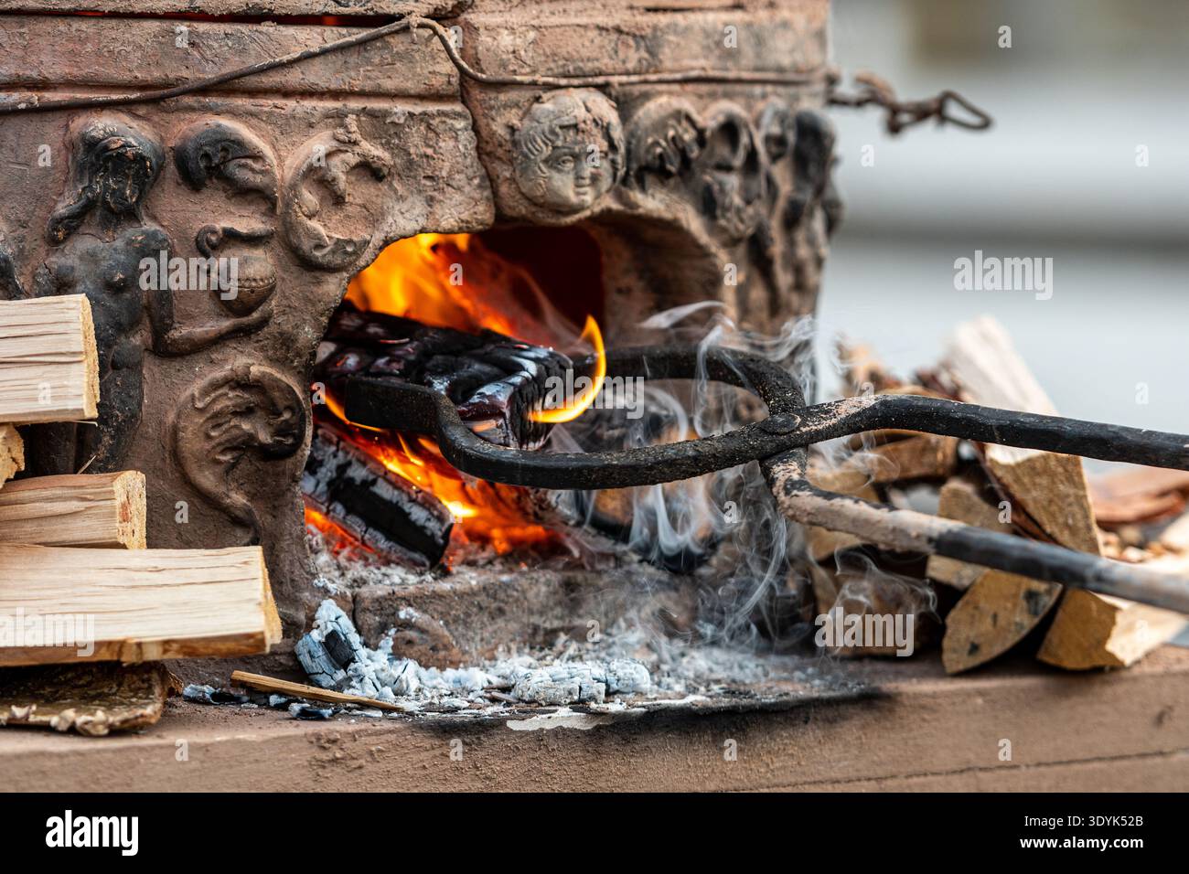I tronchi di legna da ardere ardenti di fiamme e brace all'interno di un vecchio forno tradizionale in argilla, creando una calda atmosfera rustica Foto Stock