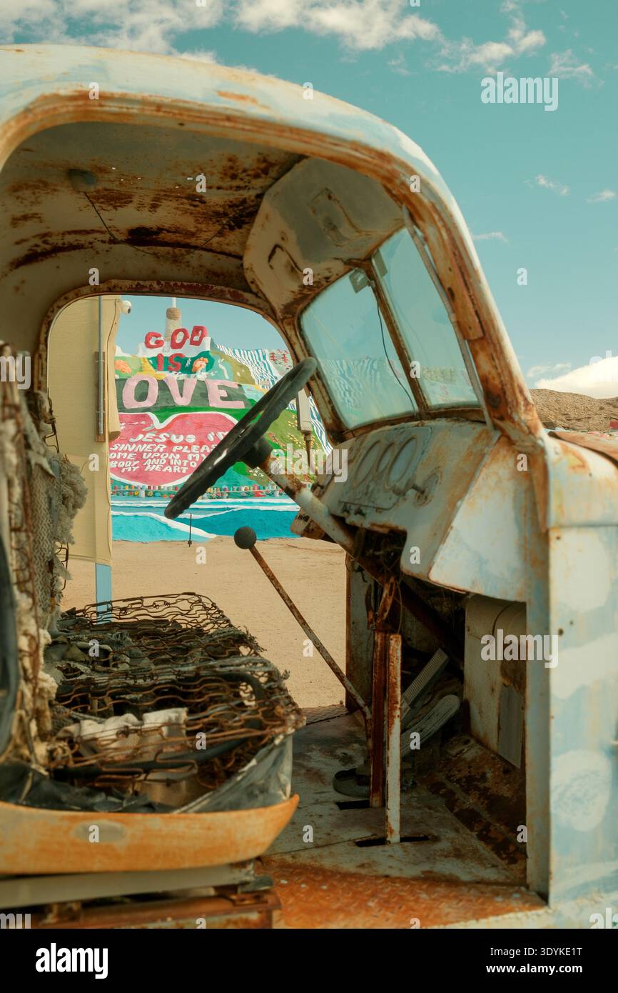 Interno del veicolo arrugginito con Salvation Mountain Visible Beyond, Slab City, California, USA. Foto Stock