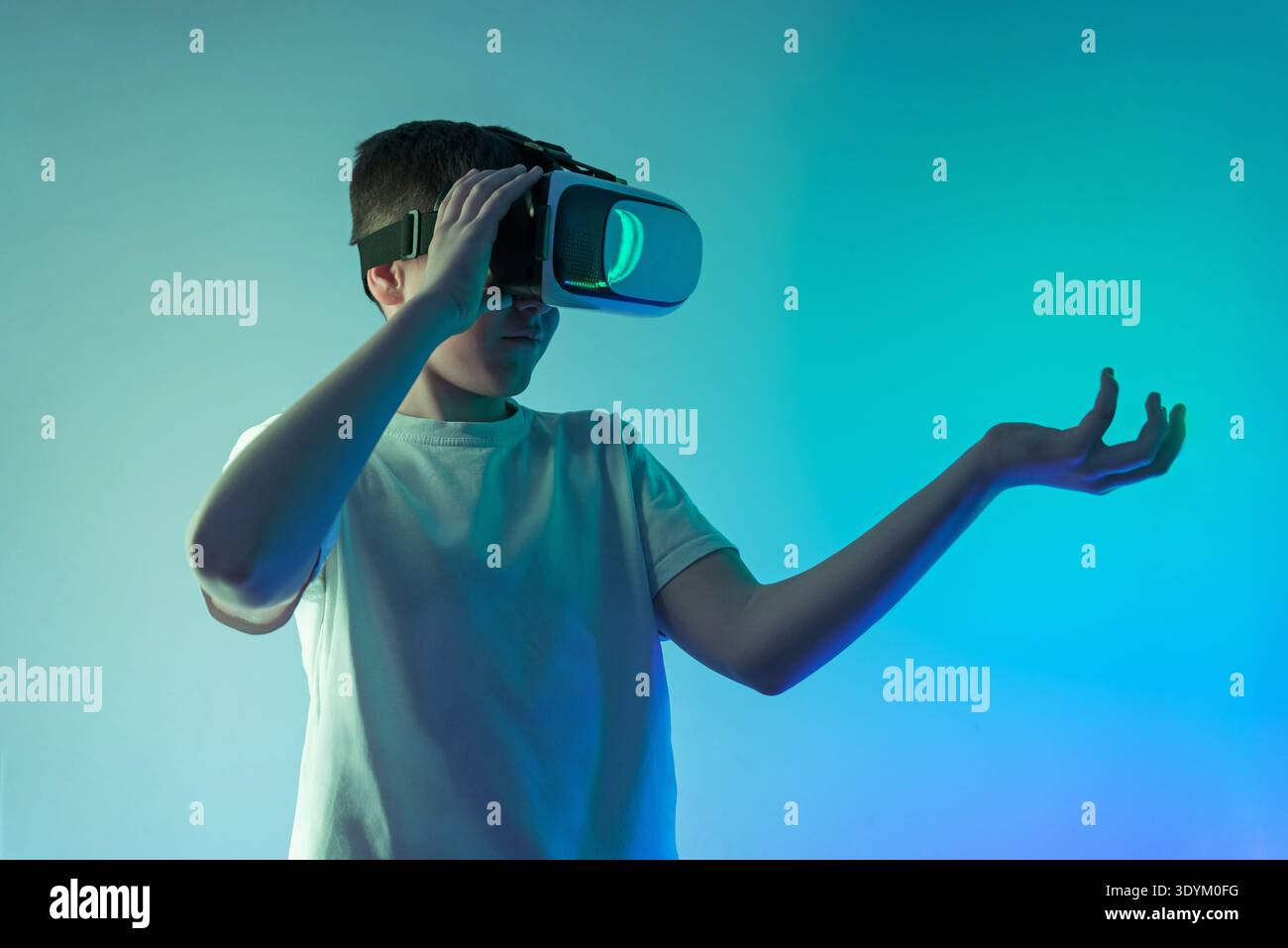 Adolescente che indossa un visore per realtà virtuale tenendo la mano aperta come se presentasse un'interfaccia ologramma, futuristico concetto di realtà aumentata con spazio di copia f Foto Stock