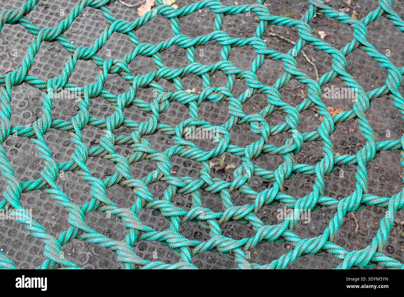 Un primo piano di una vivace rete a fune annodata turchese con un motivo circolare concentrico. Le fibre testurizzate e intrecciate creano una bobina robusta e geometrica. Foto Stock