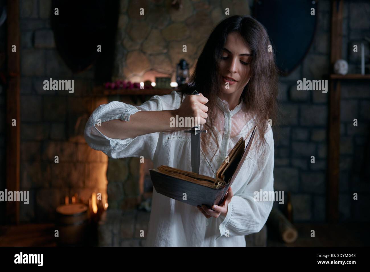 La donna in camera sacra esegue un antico rituale con erbe e lume di candela Foto Stock