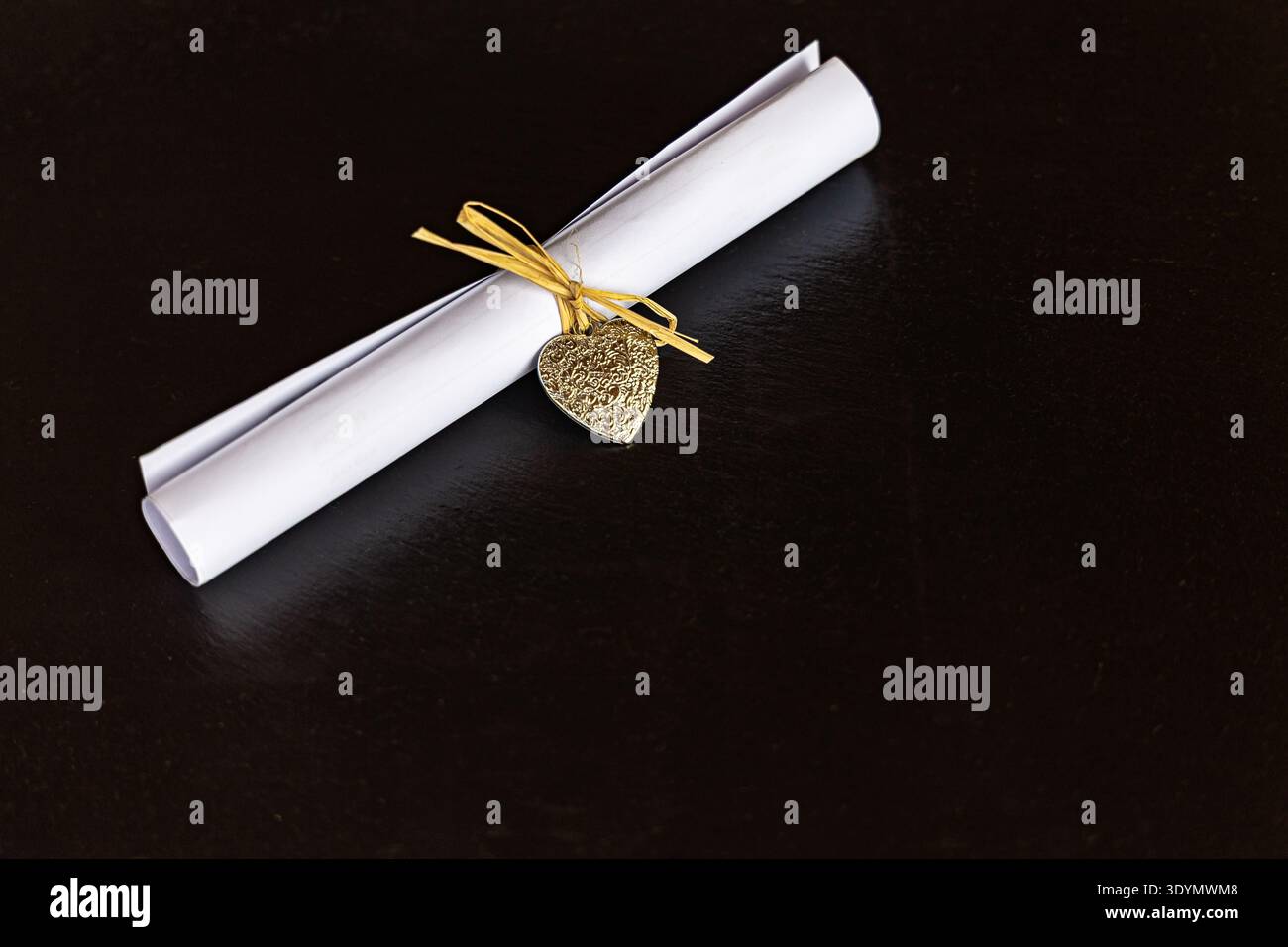 Un rotolo di carta cucito dalla paglia e una decorazione a forma di cuore su sfondo nero per il testo Foto Stock