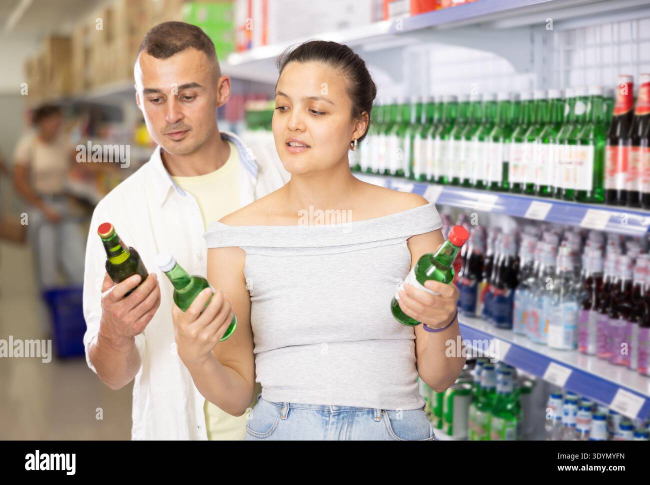 Coppia positiva che sceglie bevande alcoliche al negozio asiatico locale Foto Stock