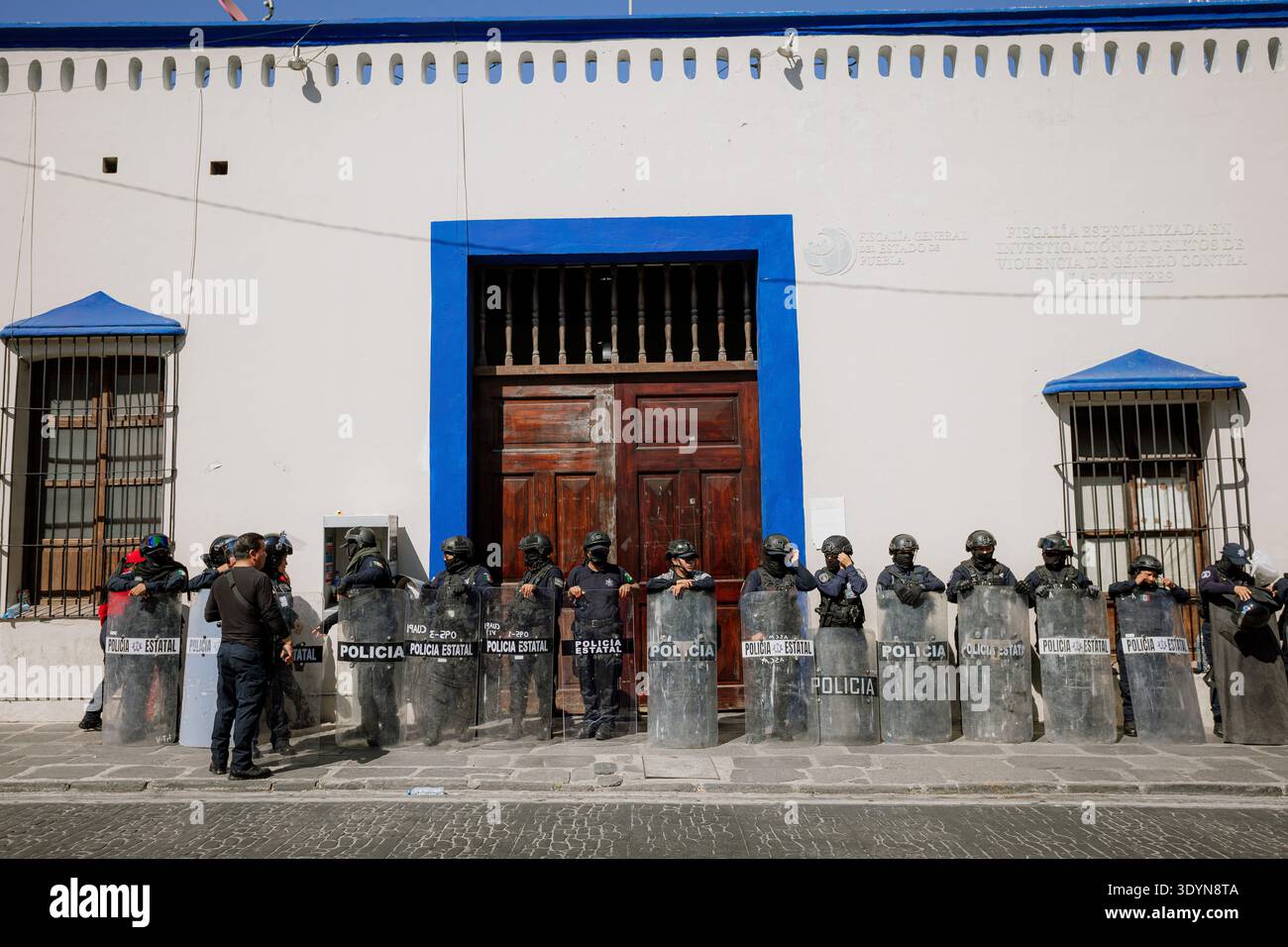 Linea di agenti di polizia con equipaggiamento antisommossa che protegge la facciata di un edificio istituzionale durante una dimostrazione nel centro di PU Foto Stock