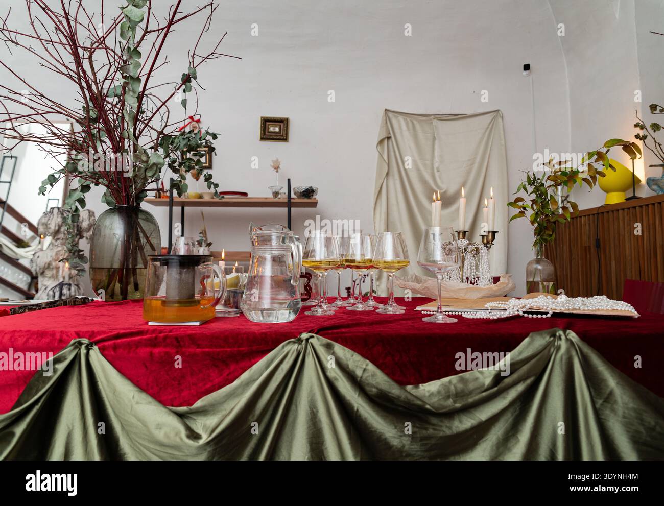 Mosca, Russia - 11 dicembre 2025 - Un tavolo in stile evento rivestito di velluto rosso e tessuto verde con file di bicchieri da vino bianco, una caraffa d'acqua, Foto Stock