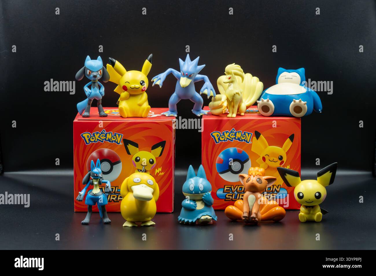 Statuette dei personaggi Pokemon tra cui Pikachu, Psyduck, Riolu e Snorlax esposte su scatole giocattolo da collezione su sfondo nero. Foto Stock