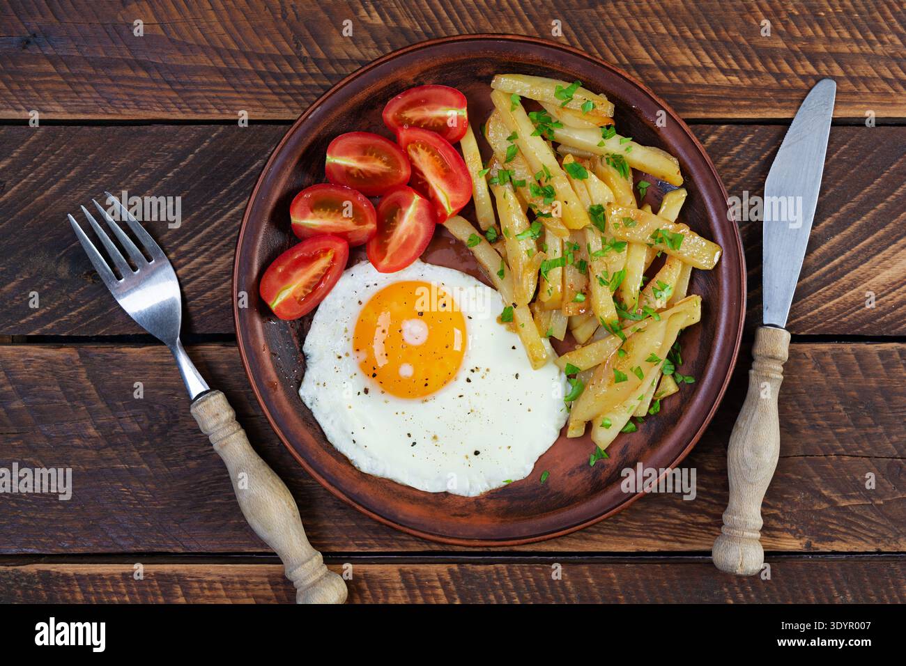 Colazione fatta in casa con uova fritte, patate croccanti e pomodori freschi Foto Stock