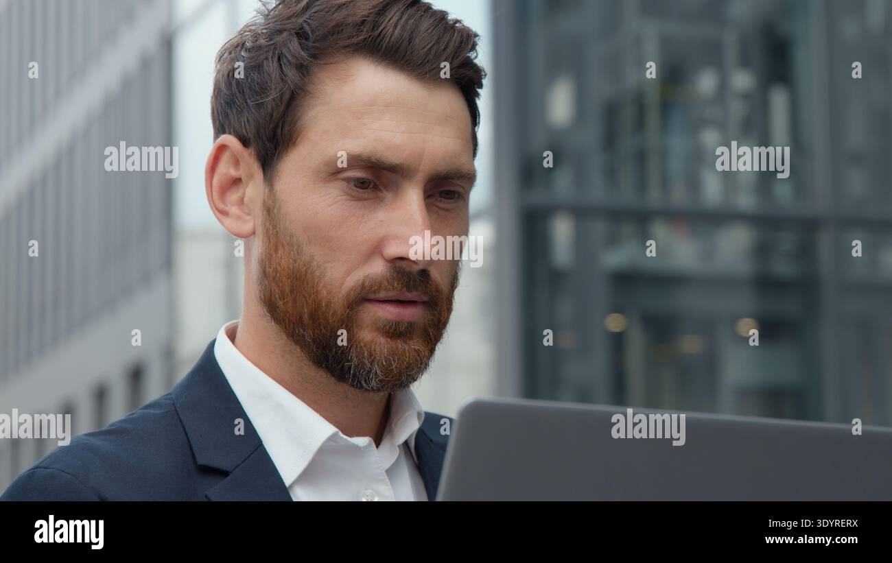 Uomo d'affari caucasico degli anni '40 incentrato sul primo piano che guarda lo schermo di un notebook uomo d'affari maturo professionista che lavora con un computer in città Foto Stock
