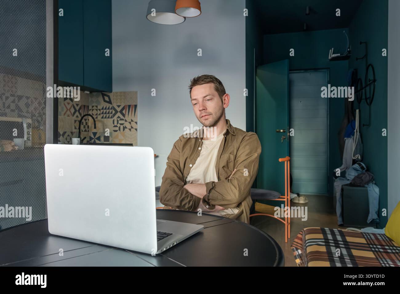 L'uomo sdraiato a letto che lavora su un laptop mentre riposa con un'espressione concentrata suggerisce concentrazione mentre digita e guarda lo schermo. Lavoro dal letto Foto Stock