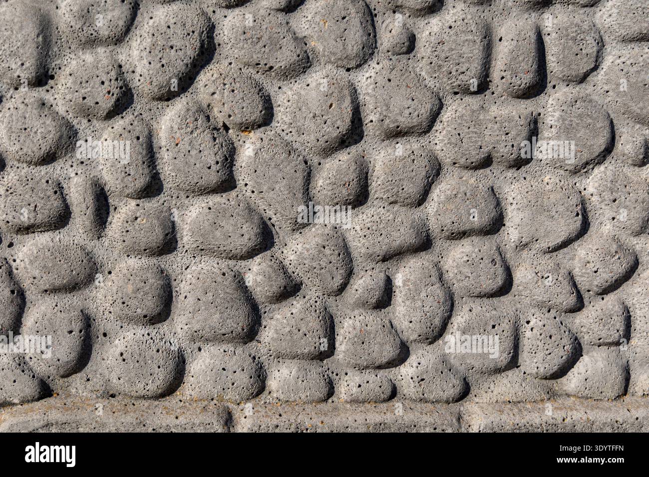 Primo piano dello sfondo della texture del muro in pietra grigio. Primo piano di una superficie grezza in pietra grigia con forme irregolari rialzate, consistenza porosa e naturale Foto Stock