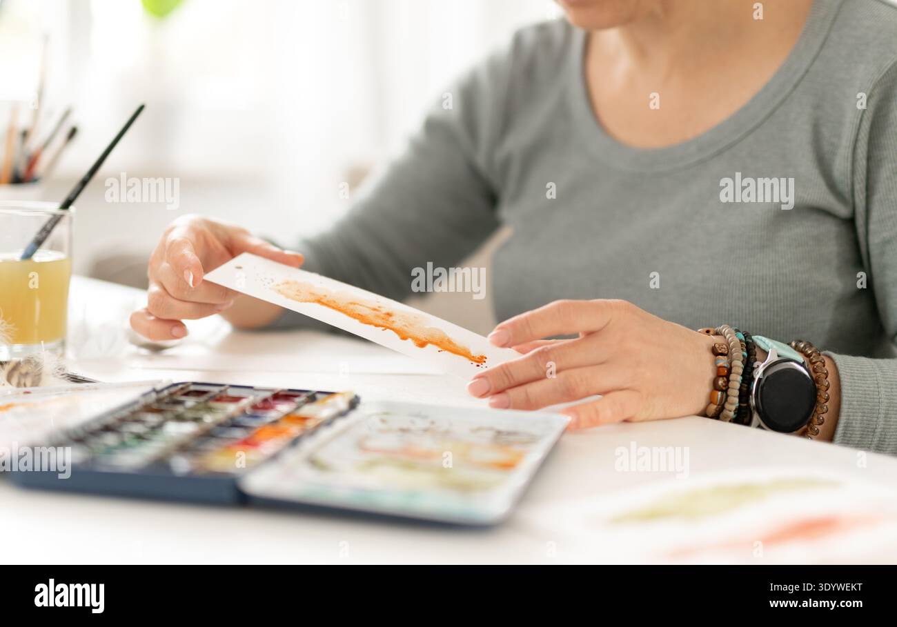 Donna che dipinge un punto astratto con acquerello mentre Un segnalibro in primo piano Foto Stock