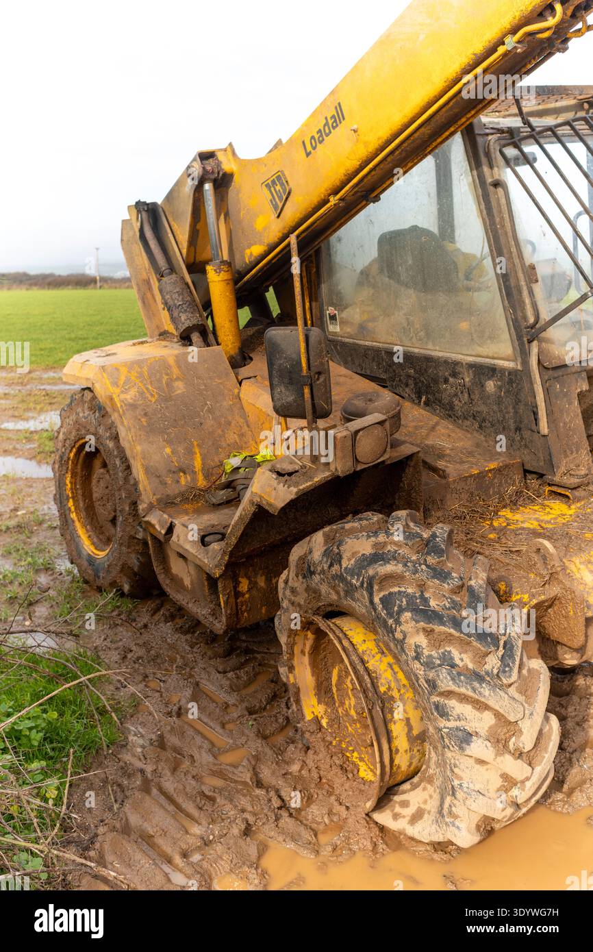 Macchina JCB bloccata su un terreno fangoso con pneumatico sgonfiato Foto Stock