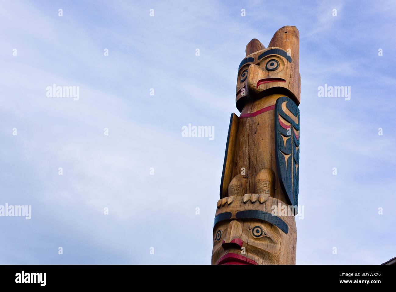 Dettaglio di un palo totem indigeno in legno intagliato contro un cielo blu morbido nel Marina Park, Comox, Isola di Vancouver, British Columbia, Canada. Foto Stock