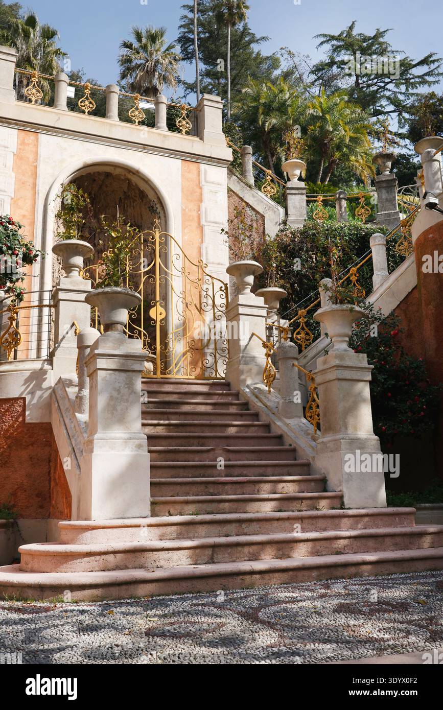 Elegante scalinata classica in pietra con porte dorate ornate nel Parco di Villa Rocca. Una maestosa scalinata in marmo caratterizzata da balaustre decorative Foto Stock