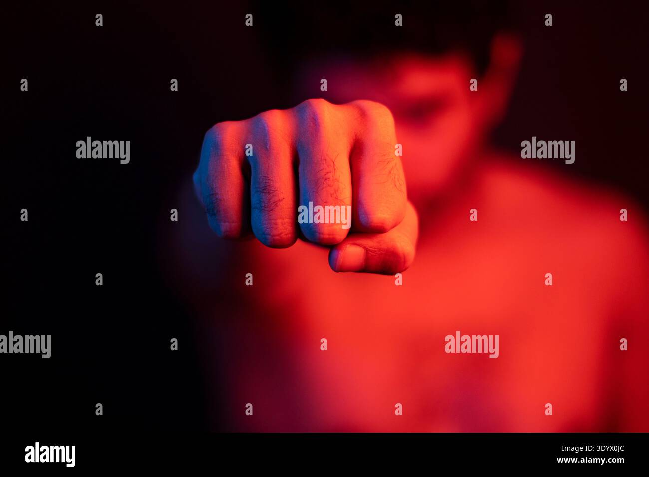 Uomo arrabbiato che pugni, pugile, allenamento con sfondo sfocato. Uomo violento che pugni, picchia. Luci rosse, violenza. Foto Stock