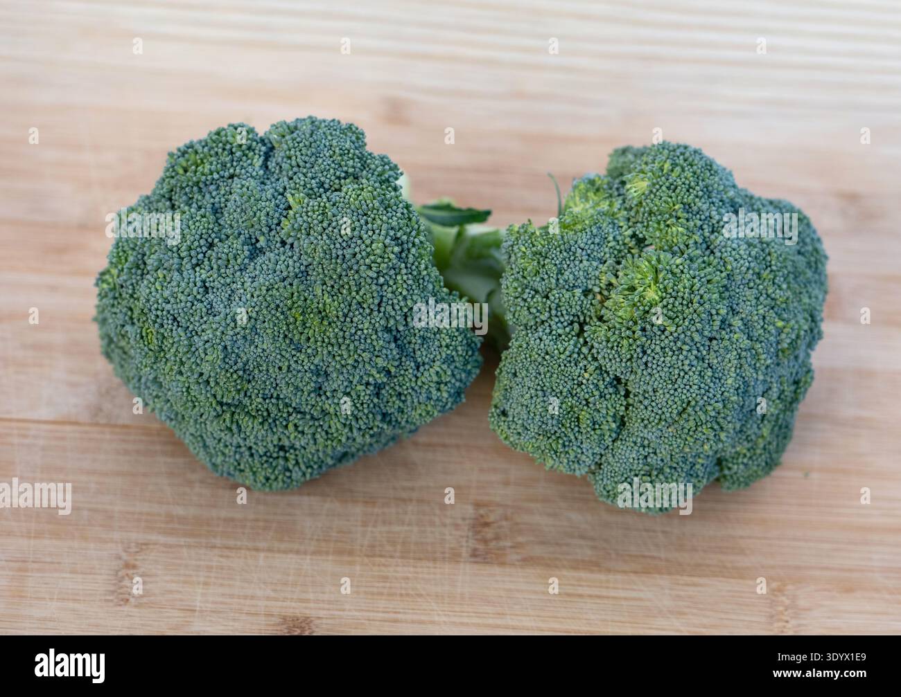 Due teste di broccoli freschi su un tagliere in legno. Sano ingrediente vegetale verde ricco di vitamine e fibre. Foto Stock