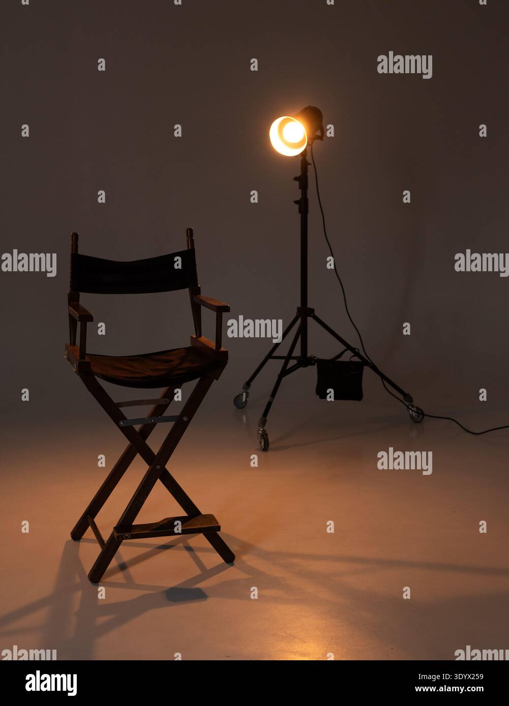 Sedia del regista vuota in uno studio buio illuminato da un unico faretto. illuminazione cinematografica. Foto Stock