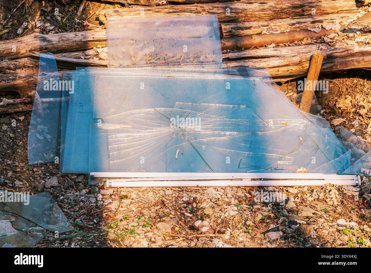 Mucchio di lastre di vetro rotte e tubi fluorescenti sul terreno con detriti Foto Stock