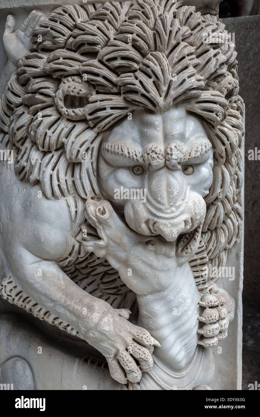 Primo piano di un leone di marmo scolpito con una criniera dettagliata e una faccia espressiva che afferrano una figura a cavallo, mostrando intricati dettagli scultorei e classici Foto Stock