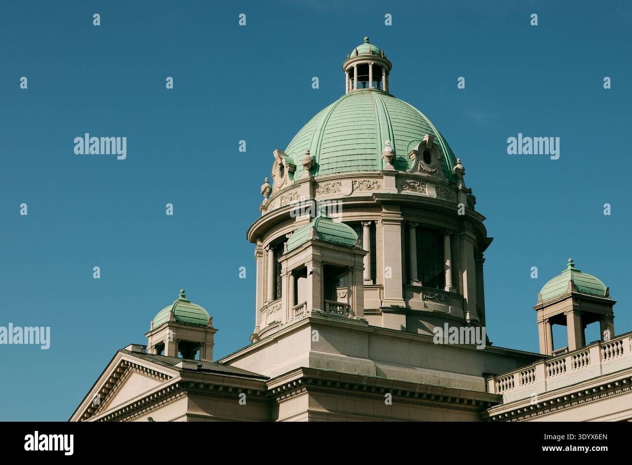 Vista ravvicinata della cupola verde e dell'architettura classica dell'edificio dell'Assemblea nazionale contro un cielo blu terso a Belgrado. Foto Stock