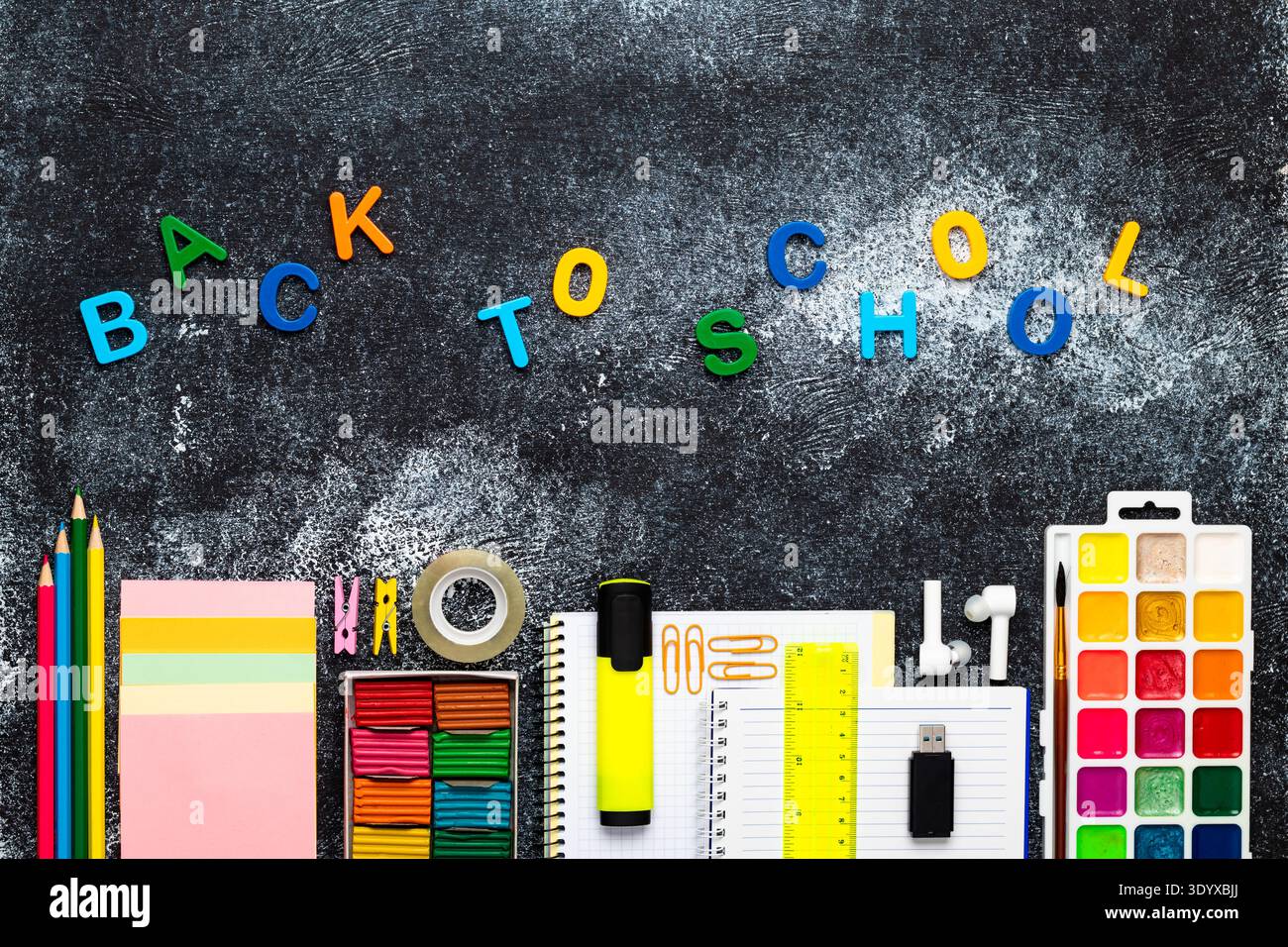 Il piano creativo Back to School è composto da lettere colorate, cancelleria, notebook, vernici e forniture per ufficio su sfondo scuro della lavagna, Bright Educat Foto Stock