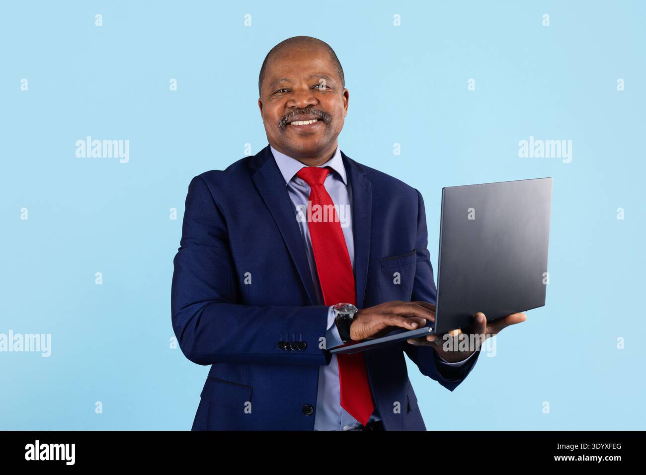 Uomo d'affari afroamericano maturo che usa un laptop sullo sfondo dello studio Foto Stock