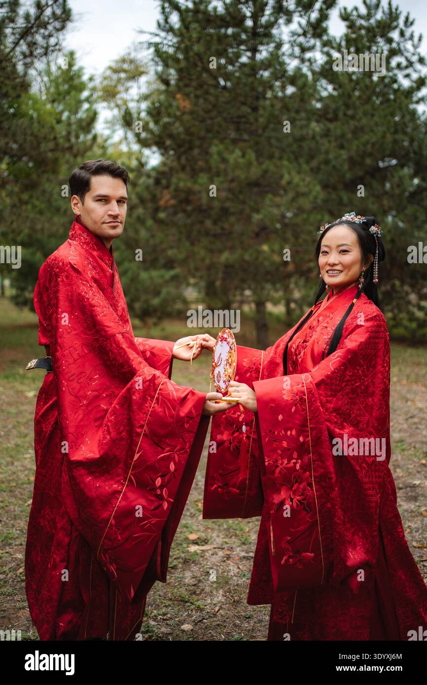 Coppia che celebra il matrimonio interculturale in tradizionale abbigliamento cinese Foto Stock