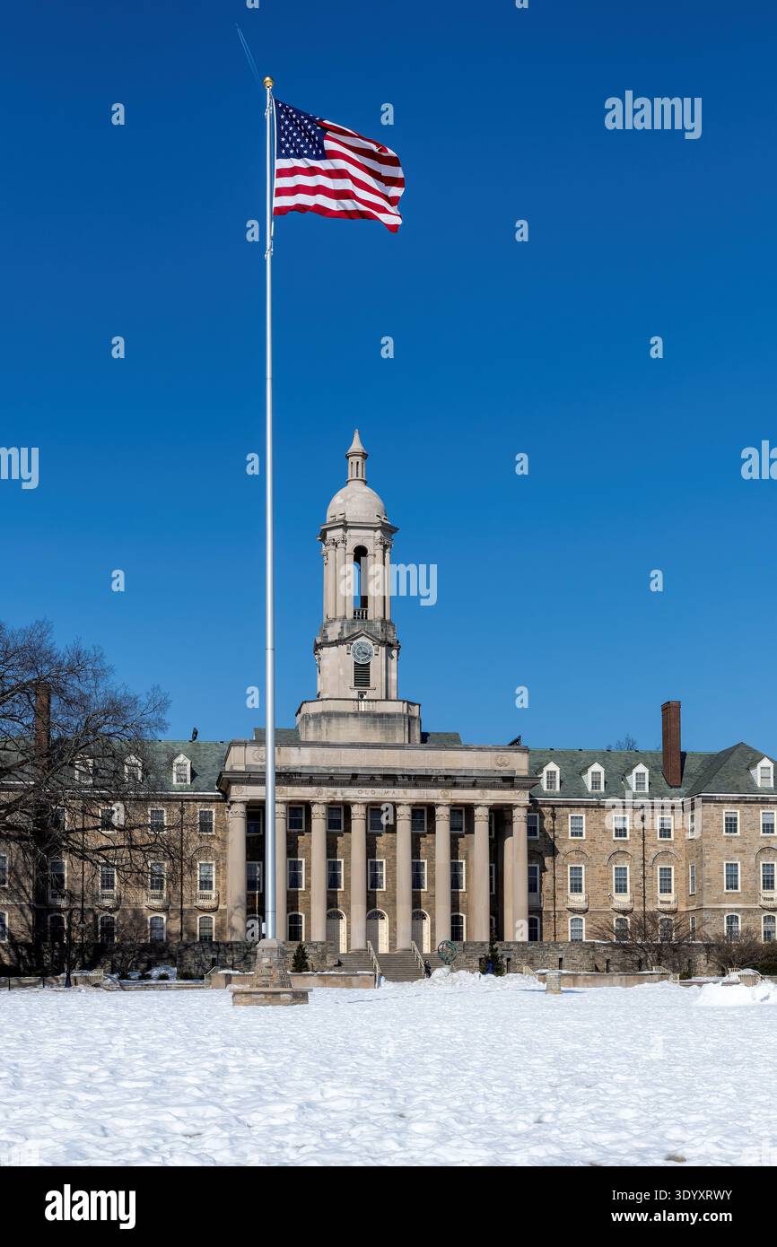 L'Old Main Building e la bandiera americana nel campus della Penn State University in inverno, State College, Pennsylvania. Foto Stock