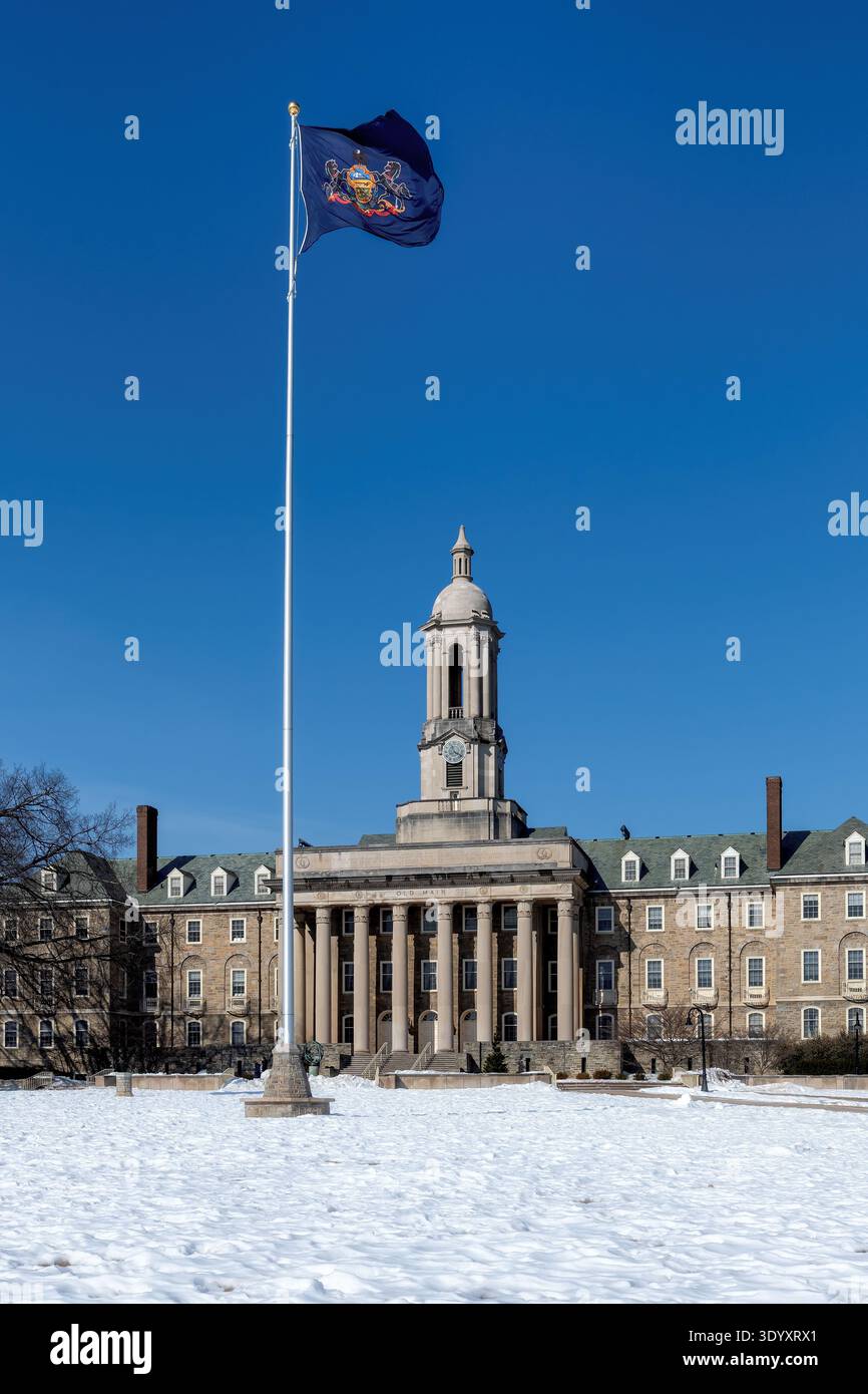 L'Old Main Building e la bandiera della Pennsylvania nel campus della Penn State University in inverno, State College, Pennsylvania. Foto Stock