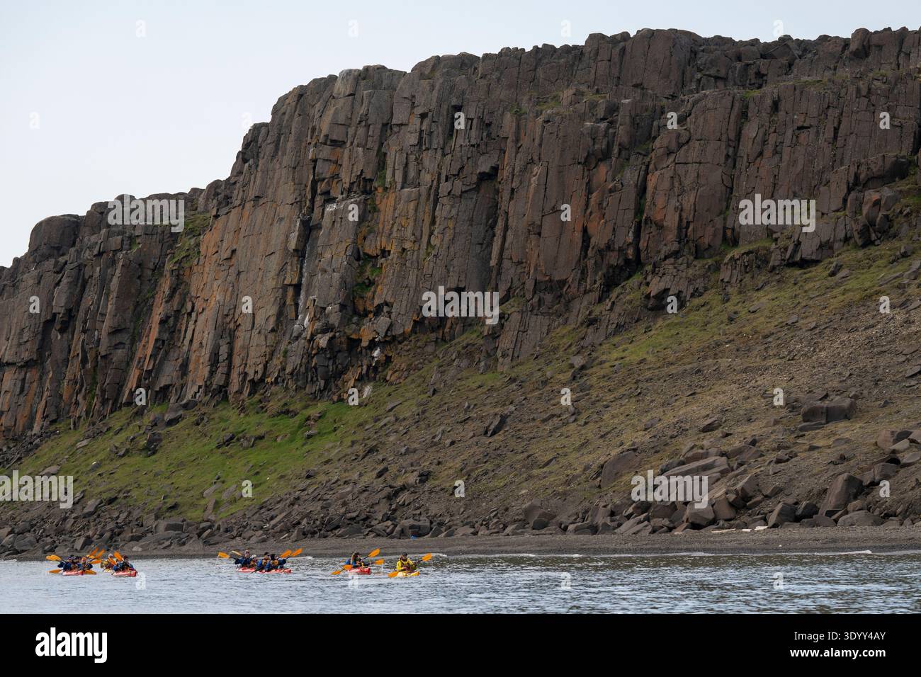 I kayak di una nave da crociera navigano nelle acque sotto le alte scogliere, Sundneset, Spitsbergen, Norvegia, Europa Foto Stock