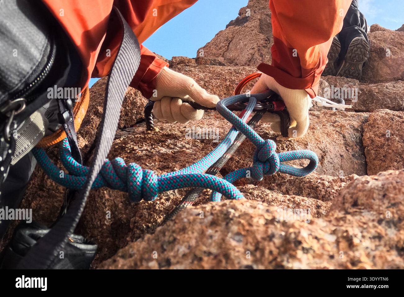 Le mani dell'arrampicatore fissano la corda alla roccia Foto Stock