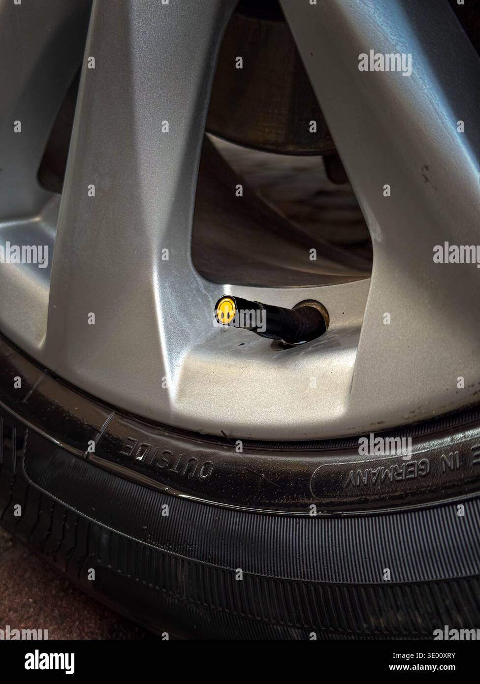 Primo piano della ruota dell'auto con stelo della valvola dello pneumatico e tappo a pressione Foto Stock