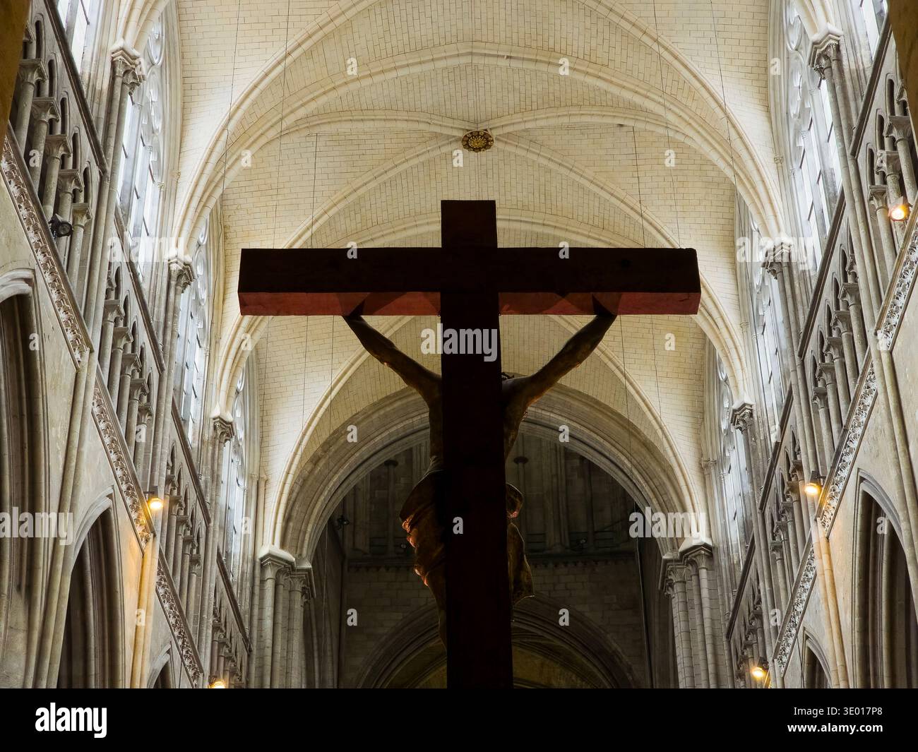Una silhouette di un crocifisso in legno si erge contro l'alto soffitto a volta gotico e gli archi a costine della Cattedrale di Rouen, immersi in morbidi ed eterei Foto Stock