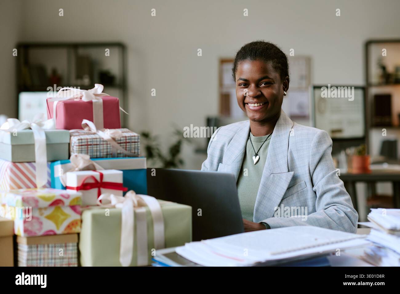 Ritratto della giovane donna nera adulta sorridente mentre lavora con le confezioni regalo Foto Stock