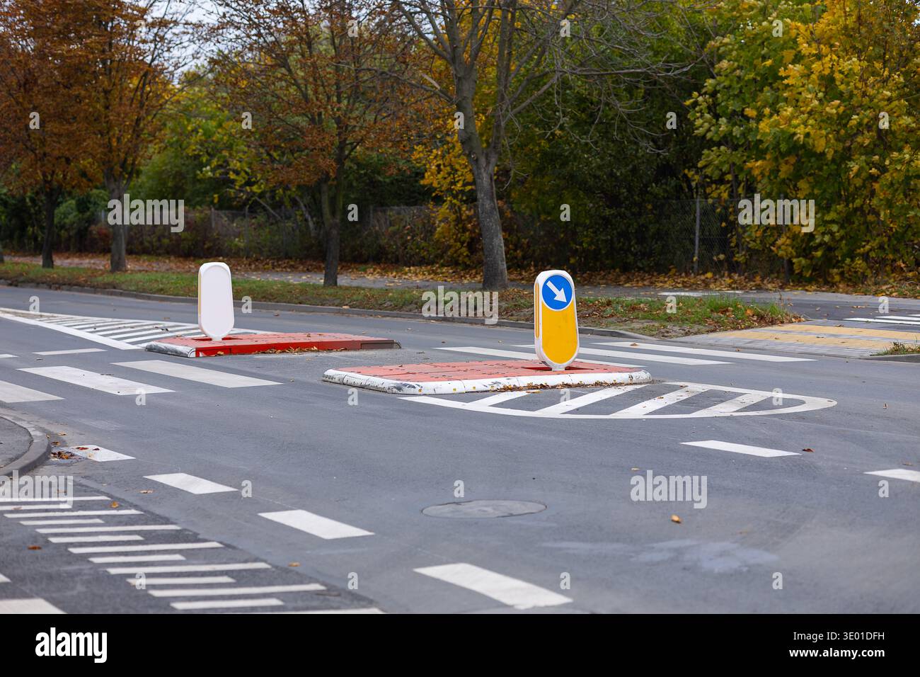 Misure ingegneristiche per calmare il traffico con un'isola pedonale sopraelevata e segnaletica direzionale su strada asfaltata. Progettazione stradale urbana Foto Stock