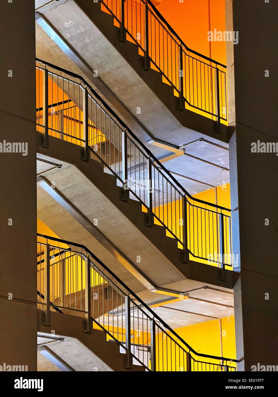 Scala in un parcheggio a più piani illuminato di notte con pareti interne gialle, Cardiff Bay, Galles, Regno Unito. Foto Stock