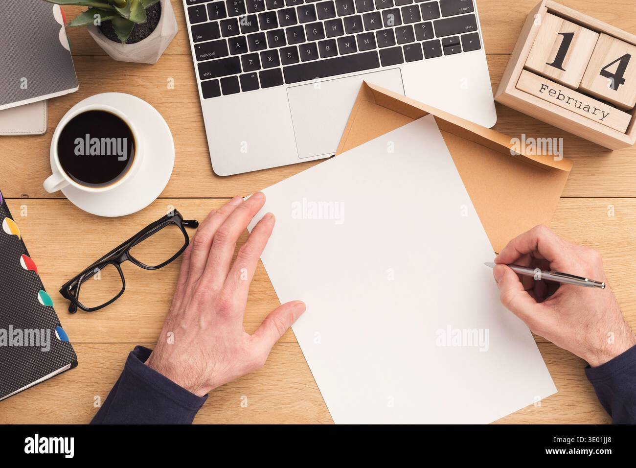 Uomo che scrive una lettera sul posto di lavoro mentre lavora Foto Stock