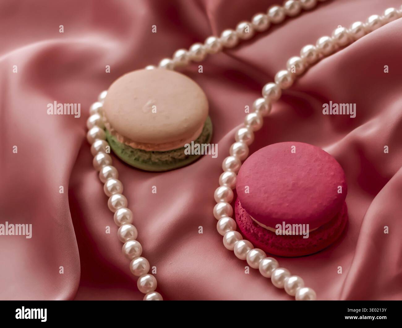 Girly, panetteria e concetto di branding - Dolce amaretti e perle gioielli su sfondo di seta, chic parigino gioielli, francese dessert cibo e torta maca Foto Stock