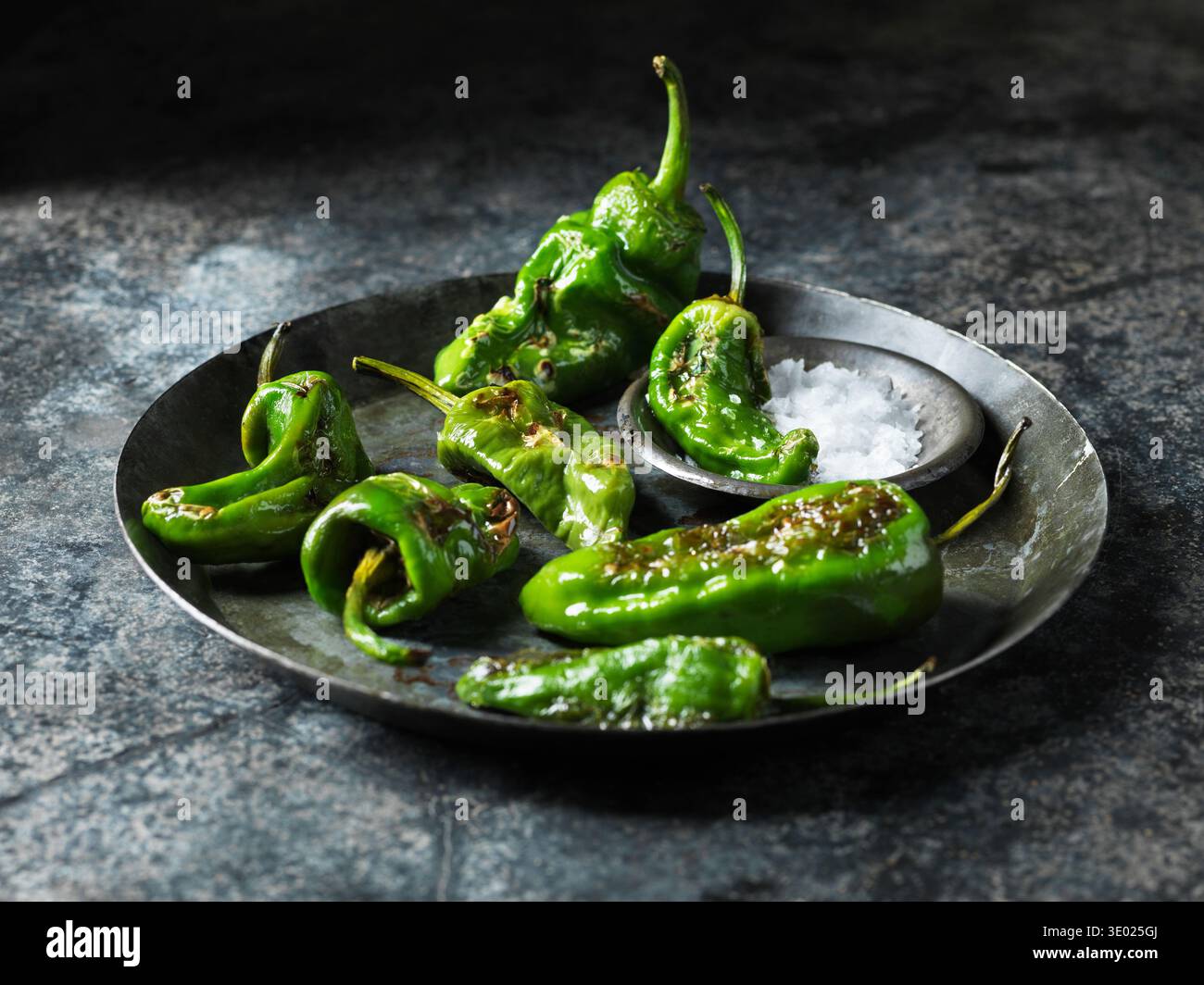 Peperoni verdi padron in piatto metallico con ciotola di sale marino Foto Stock