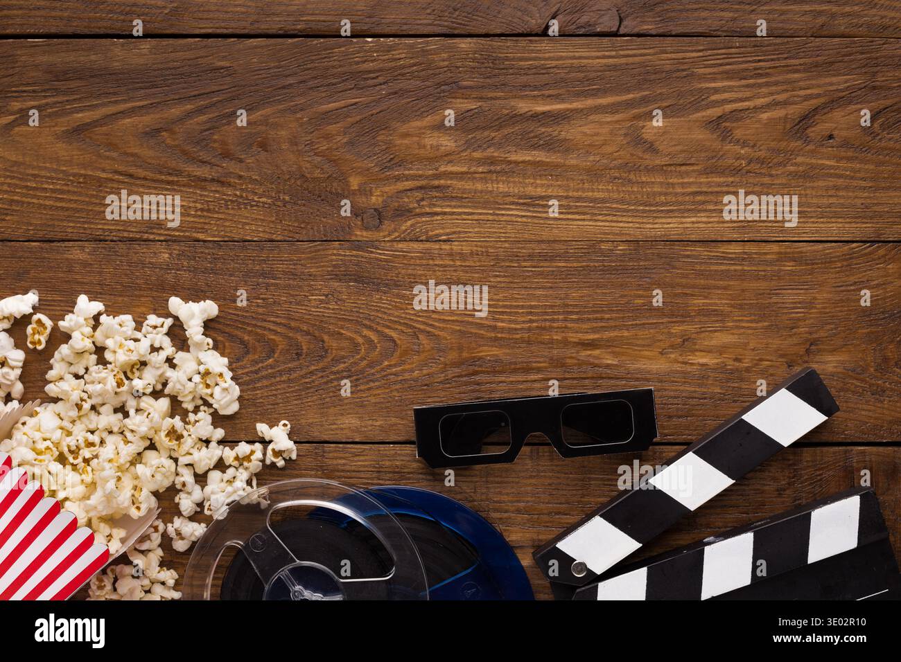 Tavoletta, bobina per pellicola e popcorn su sfondo in legno, vista dall'alto Foto Stock