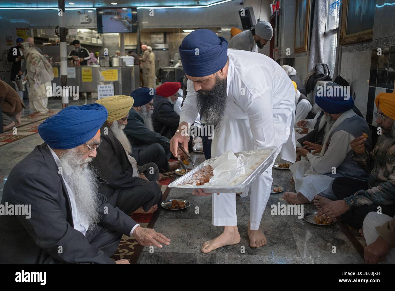 Un anziano Sikh chiede 3 da un server in una cucina comune di langar del tempio Sikh. A South Richmond Hill, Queens, New York. Foto Stock