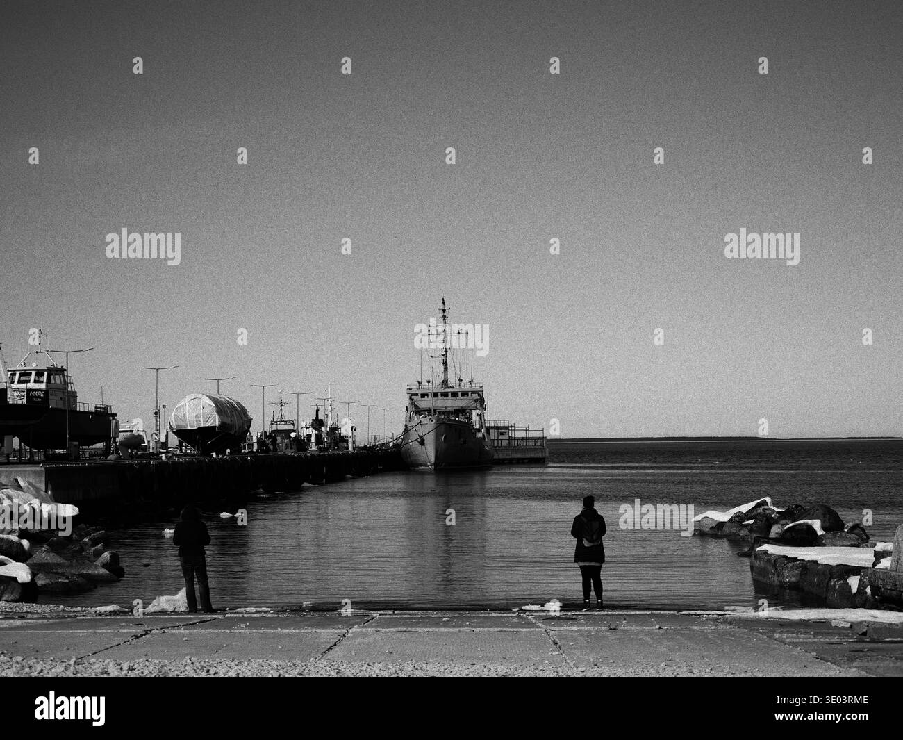 Sagome di due persone che guardano una nave ormeggiata nel porto di Tallinn. Foto Stock