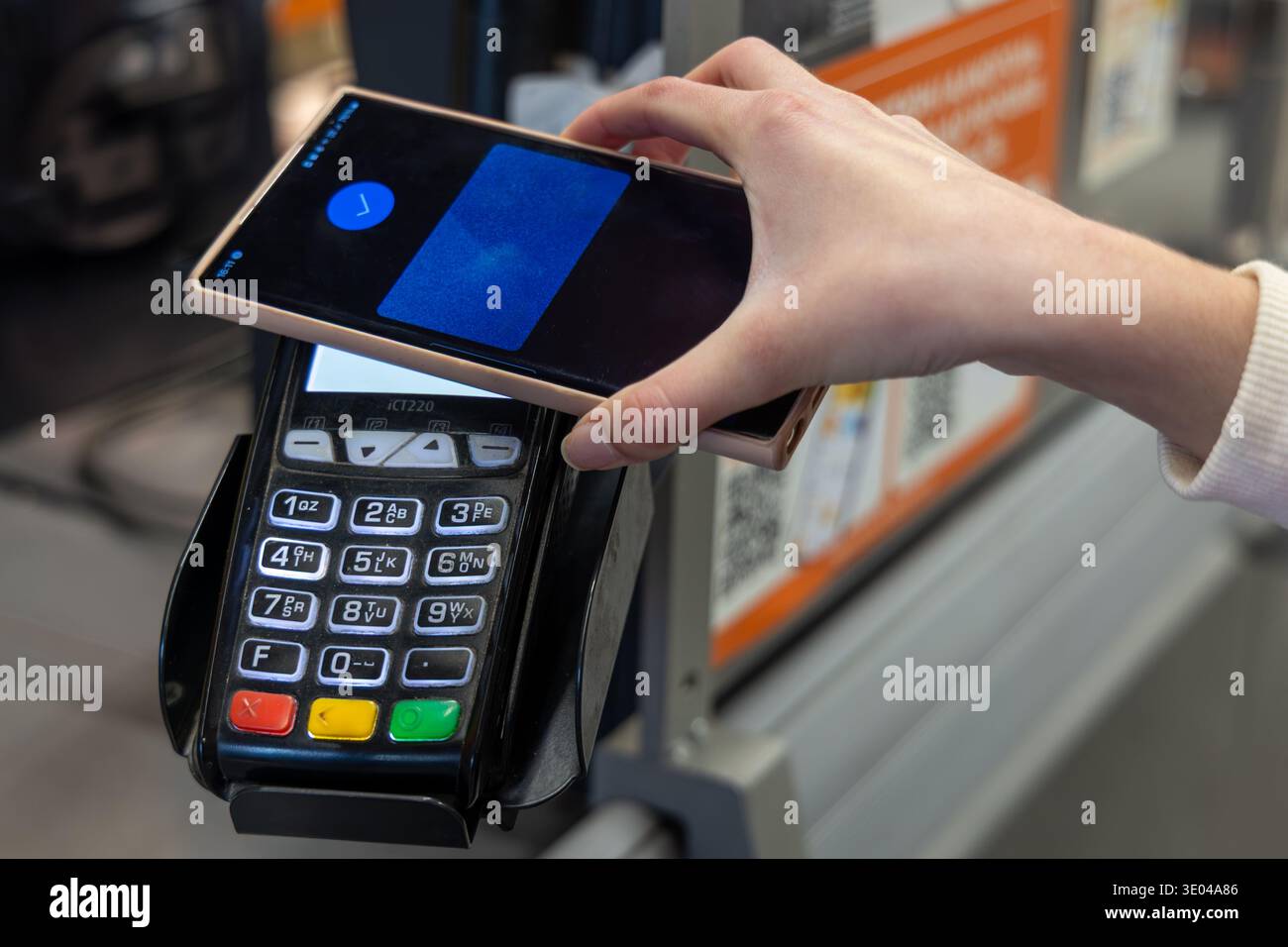 Utilizzo dello smartphone per il pagamento senza contatto nel negozio. Primo piano di un cliente che tocca uno smartphone su un terminale per carte per un pagamento veloce senza contatto in un Foto Stock