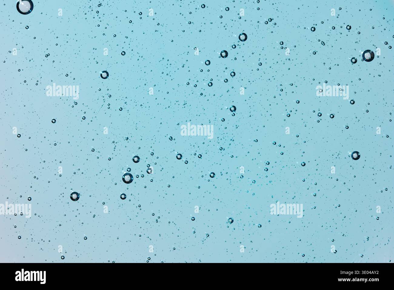 Le microscopiche bolle sospese in un liquido blu trasparente formano un motivo intricato, creando la consistenza di una piastra Petri e catturando l'essenza di sciie Foto Stock